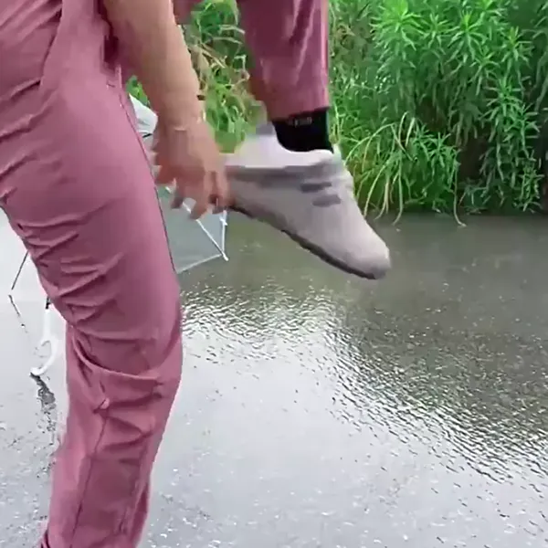 Mulher a calçar a capa de silicone por cima do ténis, à chuva